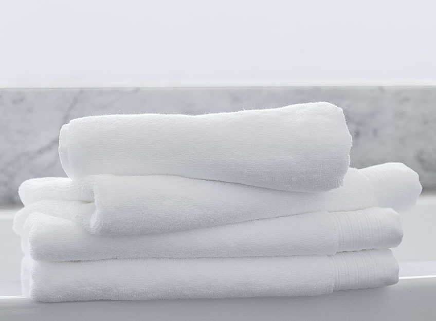 Бели кърпи на купчина в банята.