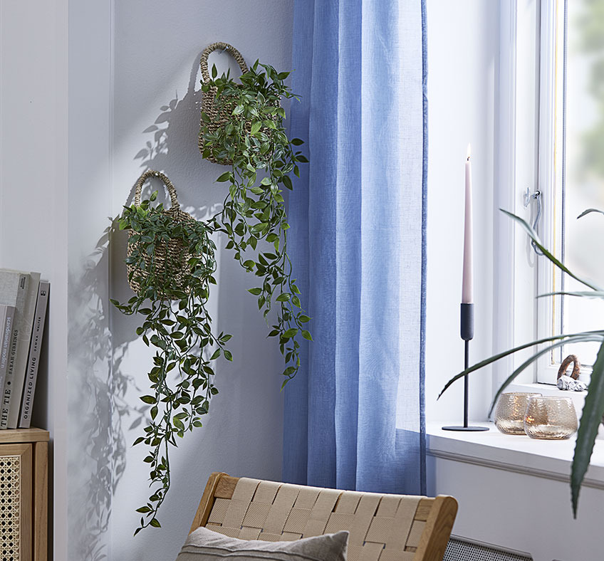Две кошници с изкуствени растения, закачени на стена на всекидневна