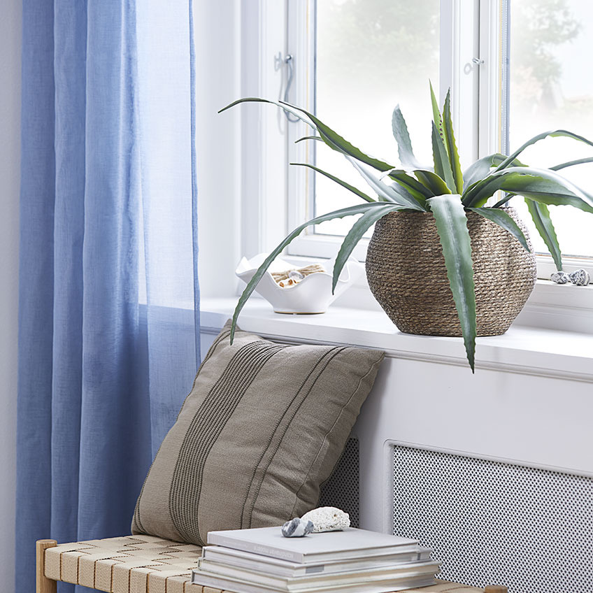 Перваз на прозорец с изкуствено растение в плетена саксия