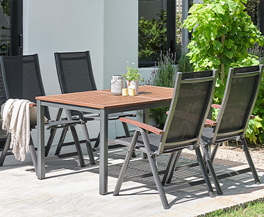 Градински комплект от маса и сгъваеми столове на слънчева тераса.