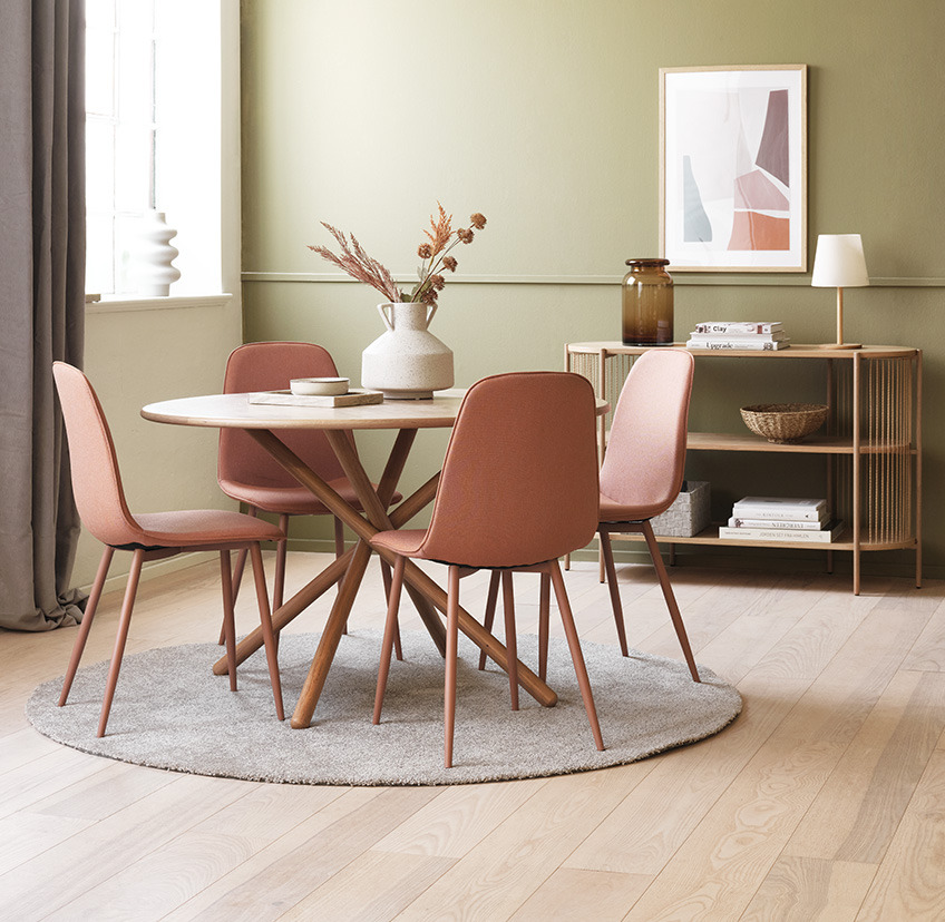 Tрапезни столове в цвят праскова около кръгла маса за хранене в дневната.