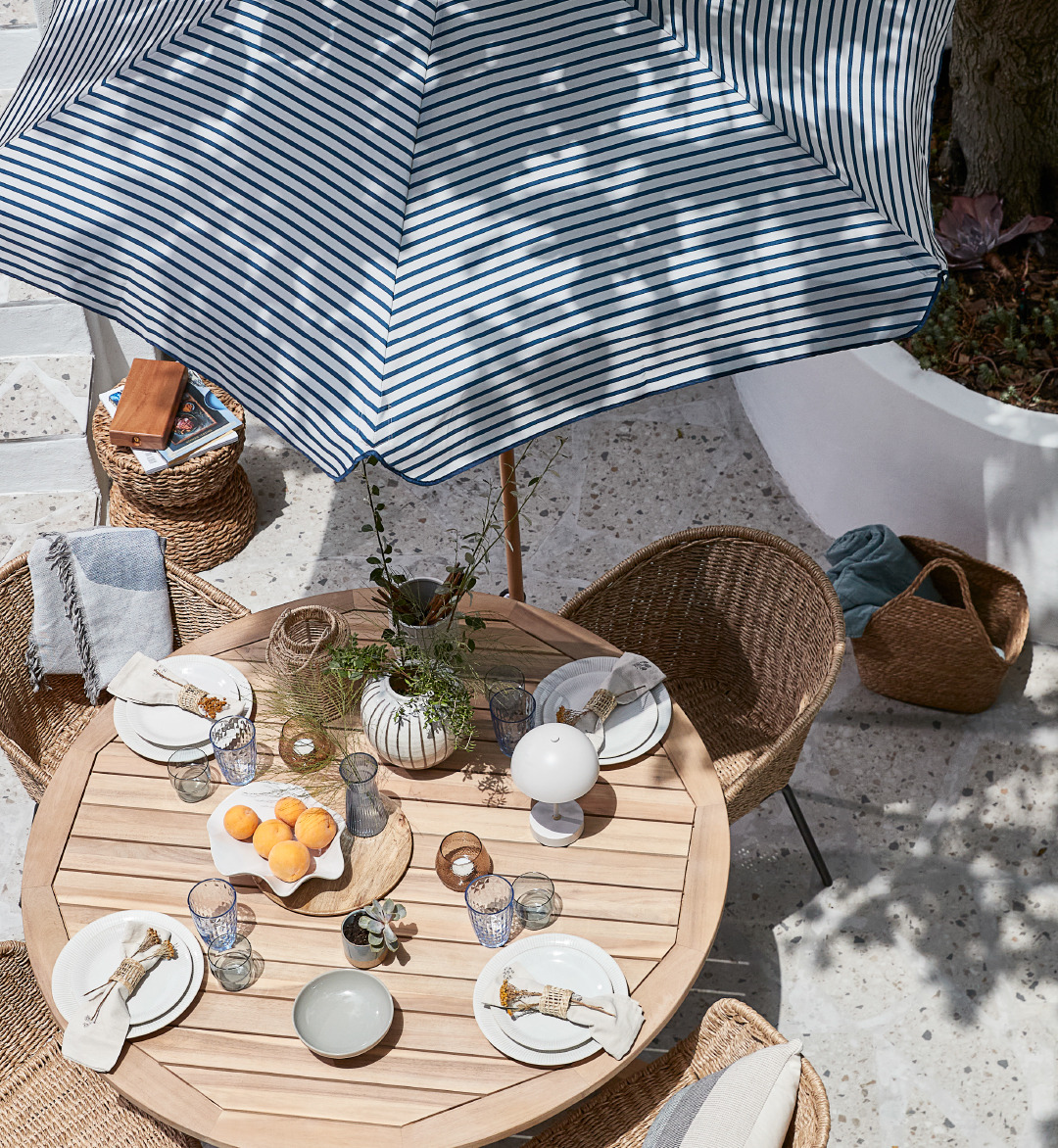 Градинска маса с четири стола и градински чадър на открито.