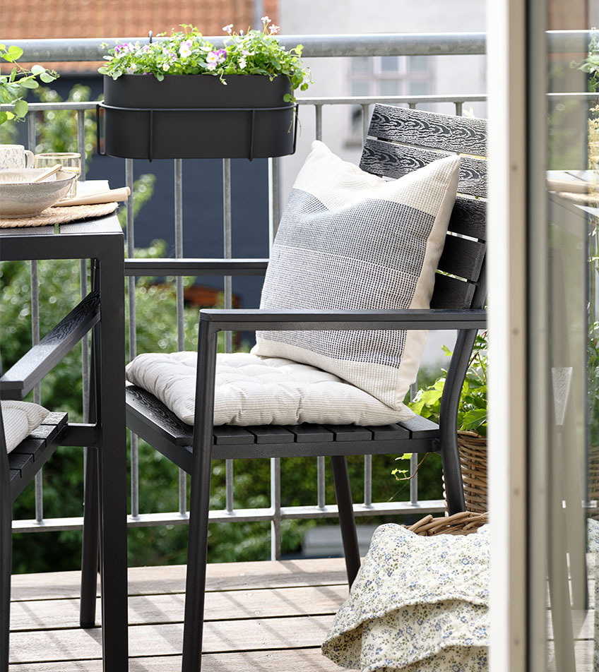 Черен градински стифиращ стол с възглавници на балкона.