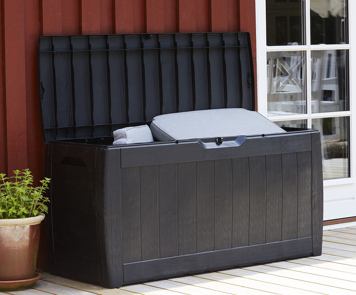 Черна кутия за съхранение на възглавници с отворен капак на вътрешен двор.