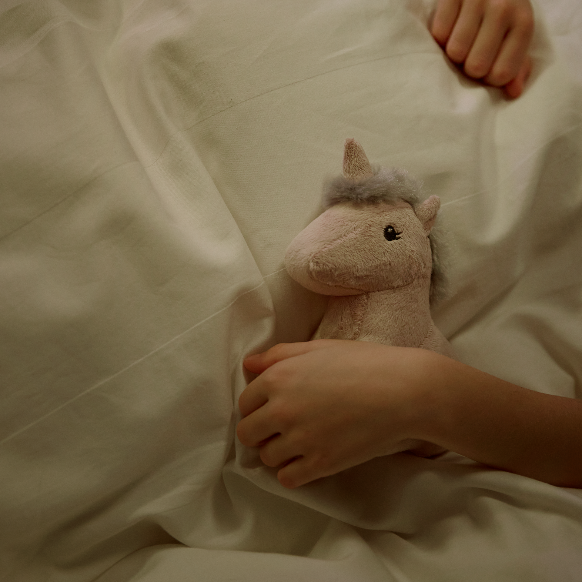 Плюшена играчка NEJLIKA Детска плюшена играчка еднорог в ръцете на дете в легло