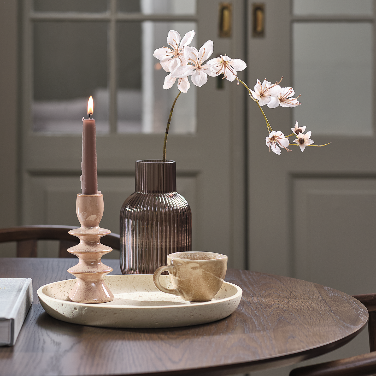 Стилно подредена маса с поднос, чаша, свещник и ваза с цвете