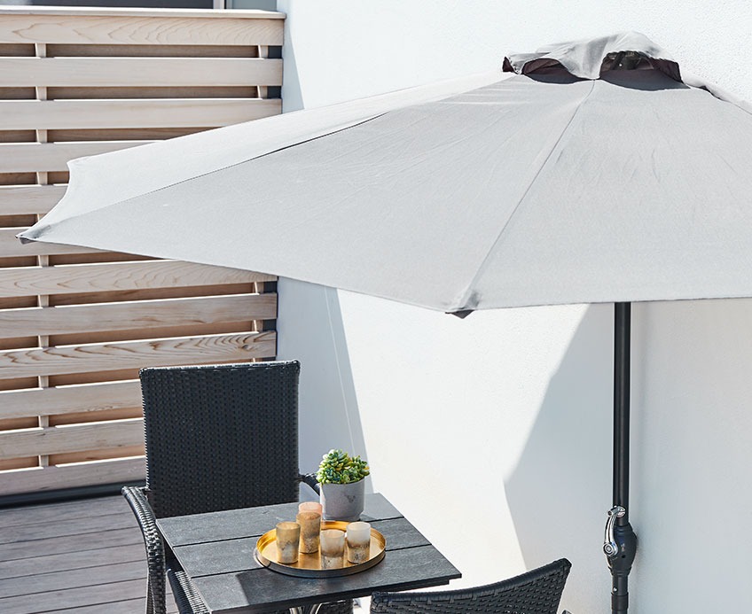 Малък балкон с чадър за слънце и комплект за бистро.