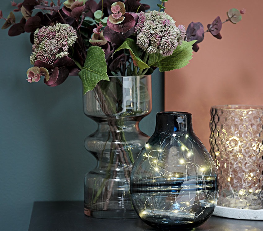 Стъклени вази със светлинни вериги и изкуствени цветя