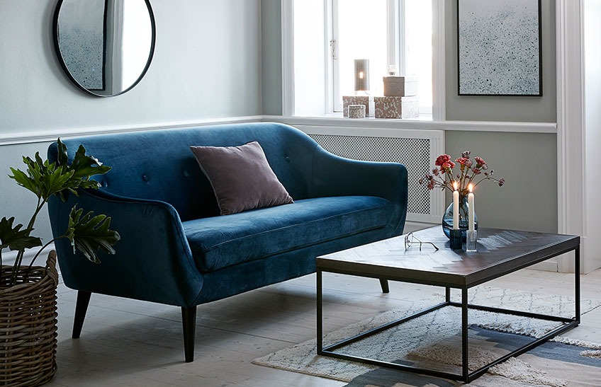 Всекидневна със син диван и минималистична маса за кафе.