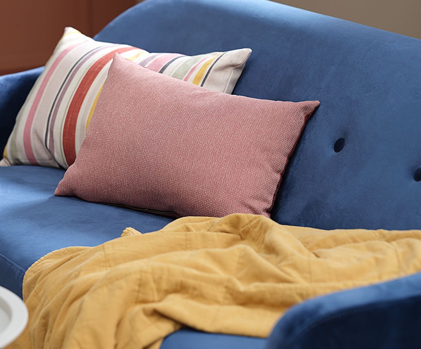 Цветни възглавници и ватирано одеяло върху син диван