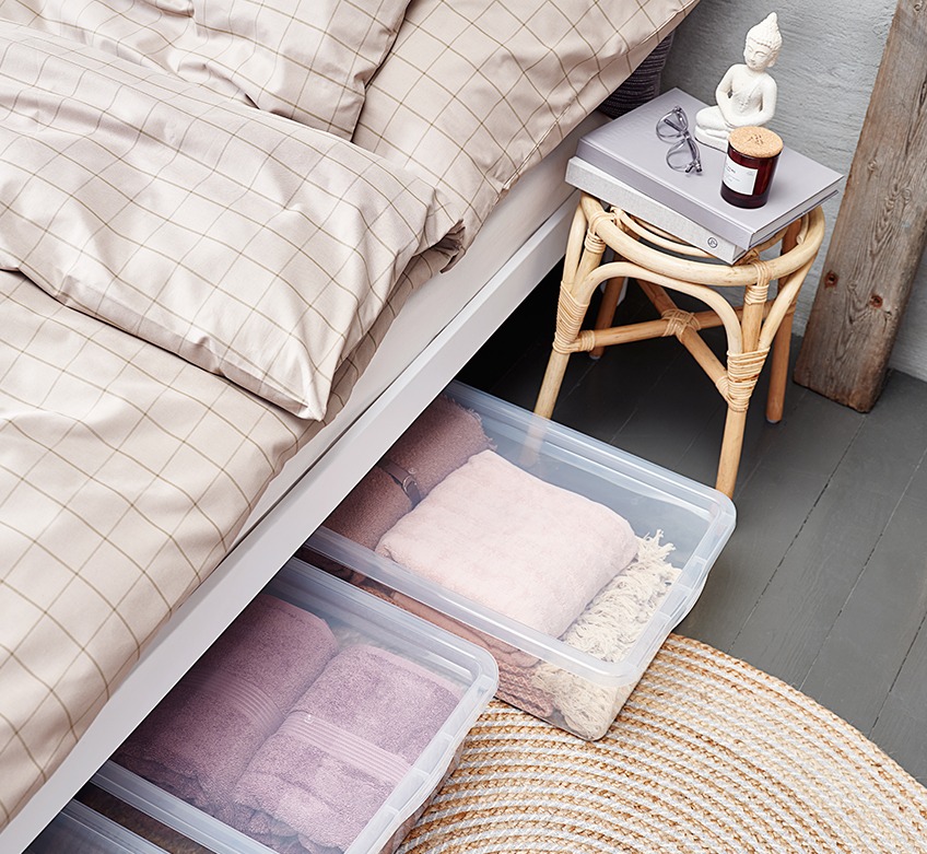 Легло със спално бельо в цвят каки и кутии за съхранение на пода.