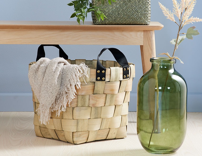Плетена дървена кошница с одеяло и стъклена ваза.