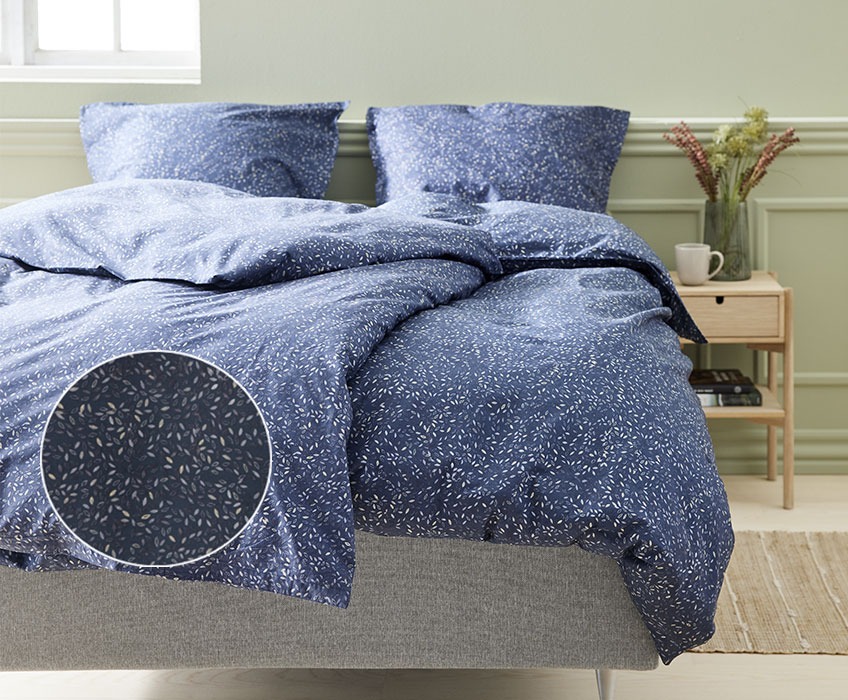Спално бельо в синьо обсипано с малки цветни листенца.