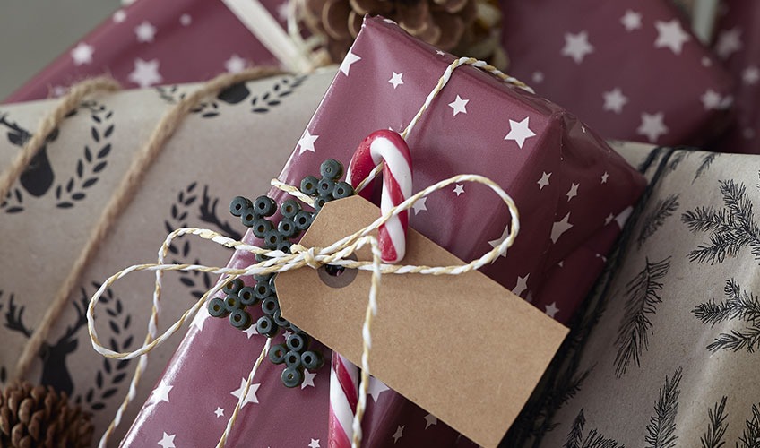Коледен подарък, опакован в хартия и украсен с бонбони и перлени мъниста
