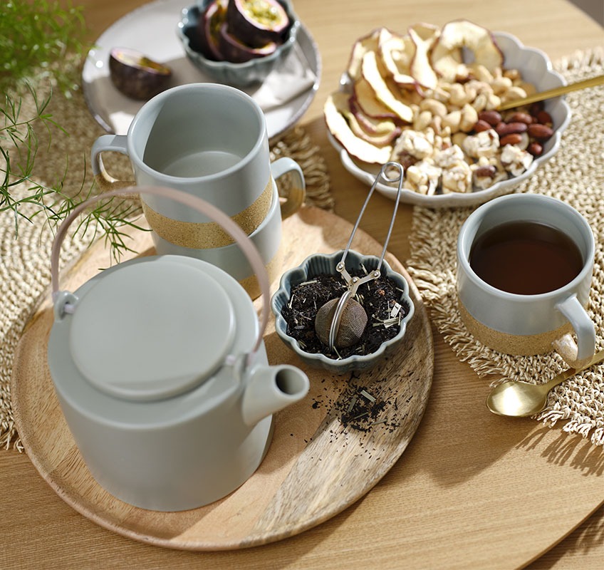 Дървен поднос със зелен чайник, чаши и малки купички със закуски и чай
