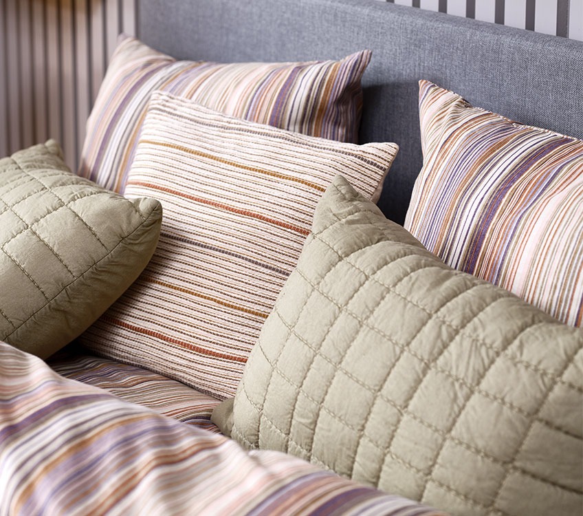 Раирано спално бельо с раирани декоративни възглавници и зелени възглавници