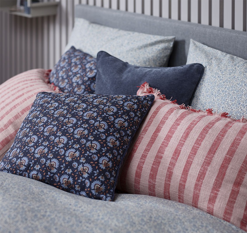 Легло с декоративни възглавници в червени и сини нюанси
