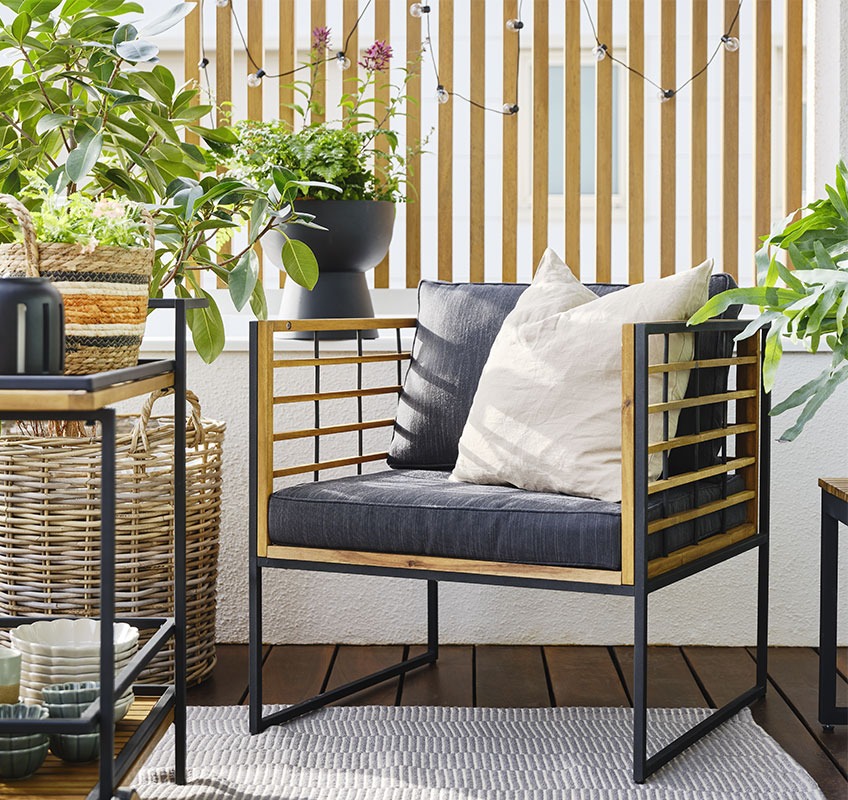 Балкон със стол за отдих от дърво и зелени растения