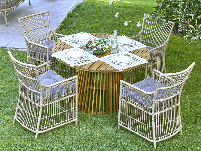 Кръгла градинска маса с центрирана основа и четири градински стола на поляна.